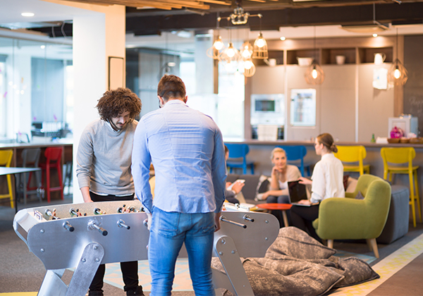 personnes jouant au baby foot dans un espace de détente d'entreprise ou de coworking