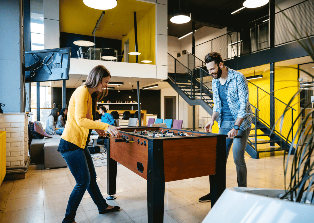 collègue de bureau jouant au baby foot dans un espace détente d'entreprise