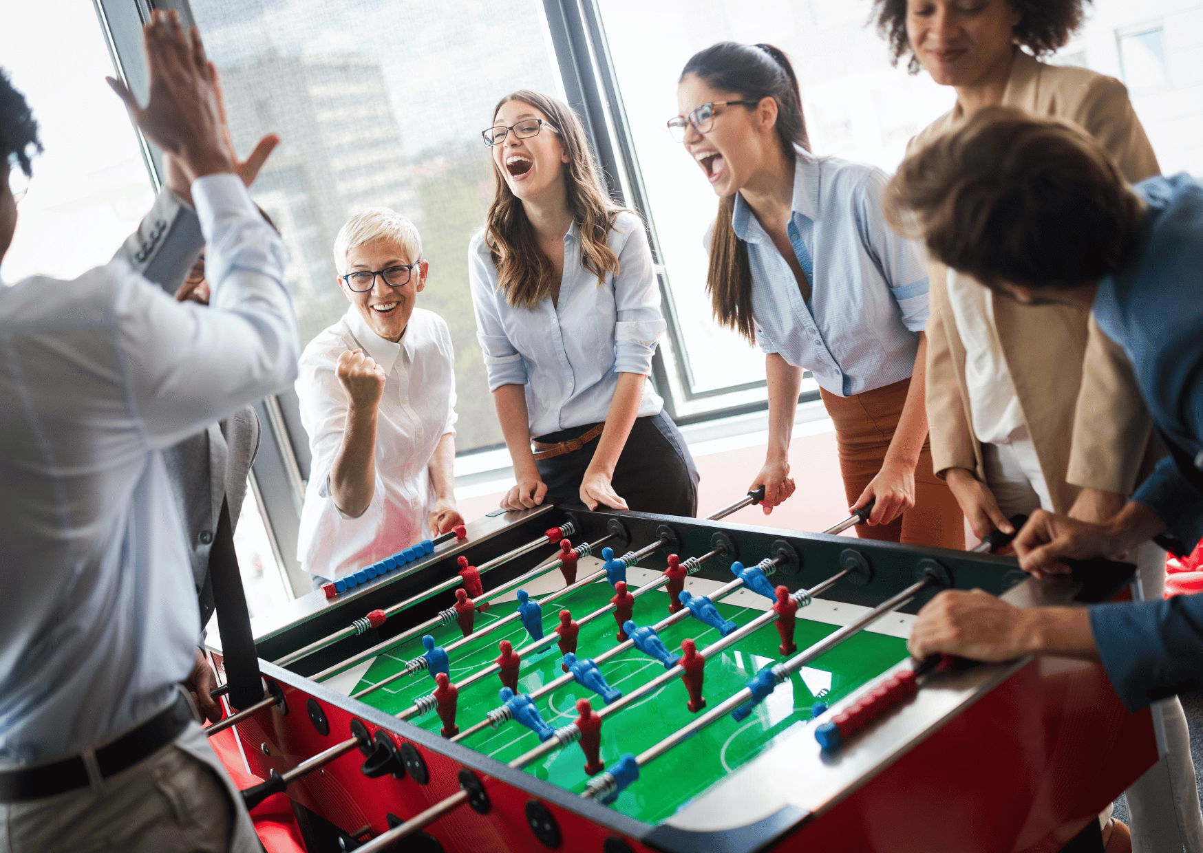 collègues de travail jouant au baby foot dans un espace de détente d'entreprise ou de coworking